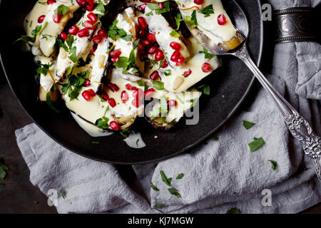 Melanzane in salsa, ricoperte di semi di melagrana Foto Stock