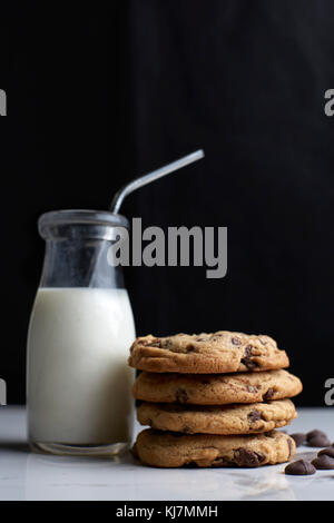 Pila di biscotti con scaglie di cioccolato e il latte in una bottiglia vintage con una paglia Foto Stock