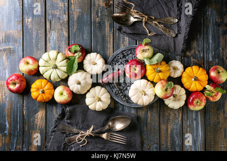 Autunno decorazione tavolo vacanza con zucche decorative, mele, foglie rosse con posate vintage, vino rosso, candela su tavola di legno. Rustico Foto Stock