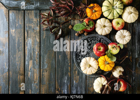 Vacanze autunnali della decorazione della tavola impostazione con zucche decorative, mele, foglie rosse su un tavolo di legno. In stile rustico, piatto laici, spazio di copia Foto Stock