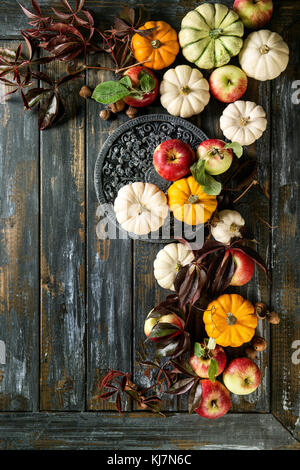 Vacanze autunnali della decorazione della tavola impostazione con zucche decorative, mele, foglie rosse su un tavolo di legno. In stile rustico, piatto laici, spazio di copia Foto Stock