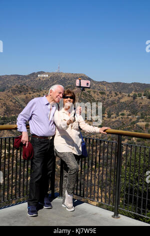 Coppia senior tenendo selfie fotografia con un telefono cellulare nella parte anteriore del segno di Hollywood al Parco Osservatorio Griffith di Los Angeles, California KATHY DEWITT Foto Stock