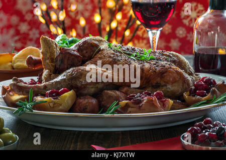 Festive anatra arrosto su un tavolo di legno con patate al forno, mele e salsa di mirtilli sul tavolo di legno Foto Stock