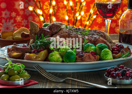 Festive anatra arrosto su un tavolo di legno con i cavoletti di Bruxelles, patate al forno, mele e salsa di mirtilli sul tavolo di legno Foto Stock