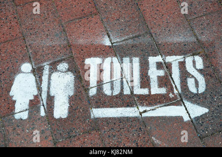 Segno dirigere verso bagni verniciato a spruzzo sul marciapiede in strada all'ingresso nsw australia Foto Stock