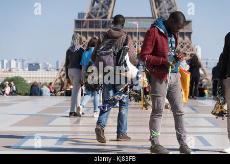Place du Trocadero, Parigi, Francia. Gli immigrati africani vendita negozio di souvenir e di miniatura Torre Eiffel, con la vera torre Eiffel in background. Foto Stock