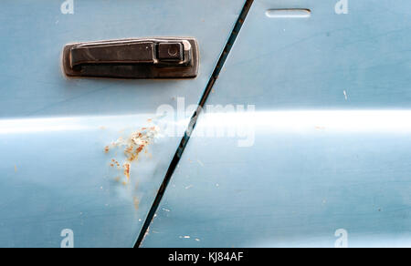 Auto maniglia della porta sul lato di un classico veicolo suv dall'era sovietica con macchie di ruggine nella luce blu vernice sbiadita Foto Stock