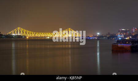 Storica quella di Howrah bridge e kolkata cityscape come visto da princep ghat in illuminazione notturna. Foto Stock