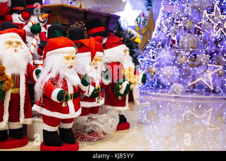 Gruppo di Babbo Natale bambole e pupazzo di bambole con illuminazione albero di Natale decorato con uno sfondo con spazio di copia Foto Stock