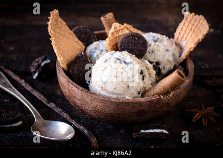 Gelato alla crema con biscotti e cono nella ciotola di legno,fuoco selettivo Foto Stock