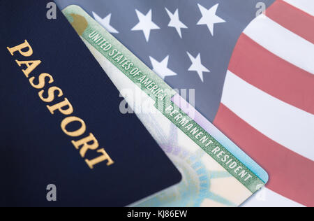 Stati Uniti d'America Permanent Resident Card, carta verde, visualizzata con una bandiera statunitense in background e un passaporto in primo piano. l'immigrazione Foto Stock