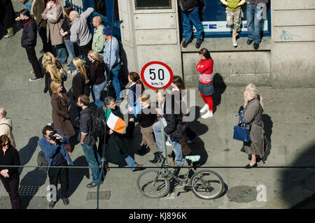 Uomo in piedi su una bicicletta guardando irlandese forze militari parade presso il 1916 Pasqua Rising commemorazione marciando attraverso il centro della città di Dublino Irlanda Foto Stock