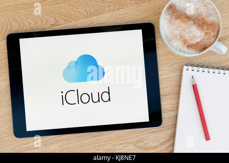 Il sito web di iCloud funzioni su un iPad dispositivo tablet pc che si appoggia su una tavola di legno accanto a un blocco note e matita e una tazza di caffè (editoriale solo) Foto Stock