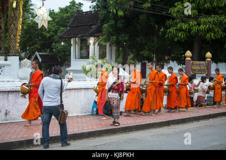 Luang Prabang, Laos - 19 novembre 2017: I toristi scattano foto dei monaci buddisti sulle elemosine tradizionali che danno ogni giorno a Luang Prabang, Laos. Foto Stock