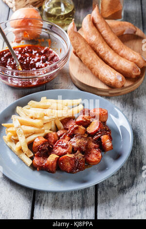 Tedesco tradizionale currywurst - pezzetti di salsiccia con salsa al curry e patatine fritte. Vista superiore Foto Stock