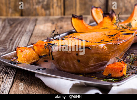 Zucca arrosto con timo e smalto balsamico sulla parte superiore su tavola in legno rustico, autunno accogliente piatto Foto Stock
