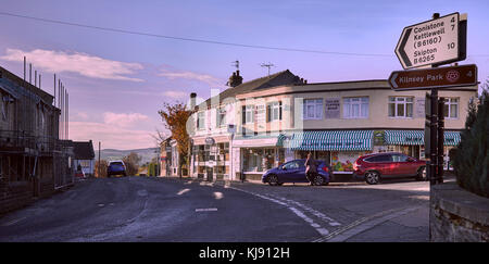 Giunzione tra B6265 e back lane per Conistone sul tardo pomeriggio autunnale in Grassington. North Yorks. fila di negozi. Deli, News, caramella mou gelato Foto Stock