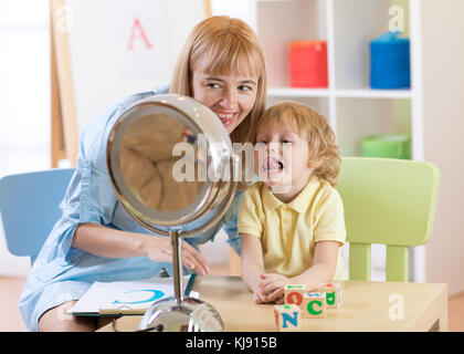 Carino bambino ragazzo di logopedista ufficio. kid rende gli esercizi di lingua insieme con l'insegnante. Foto Stock