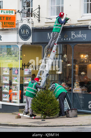 Persone vestite con cappelli di Natale mettendo su un albero di Natale in Arundel, West Sussex, in Inghilterra, Regno Unito. Foto Stock