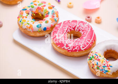 Preparazione per la vacanza. colorato ciambelle americane su sfondo rosa Foto Stock