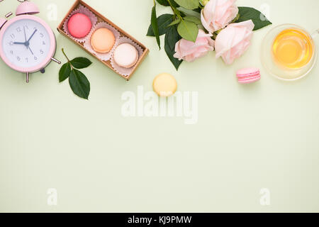 Amaretti colorati e rose fiori con confezione regalo su un tavolo di legno. dolce macarons in confezione regalo. vista superiore Foto Stock