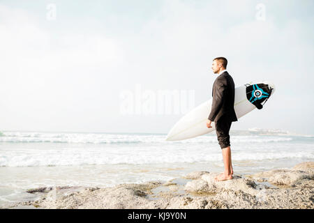 Un imprenditore holding è la tavola da surf dopo una lunga giornata di lavoro Foto Stock