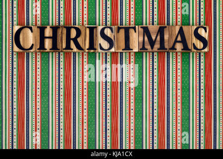 La parola natale effettuate dal blocco di legno lettere su un colorato sfondo striato. Foto Stock