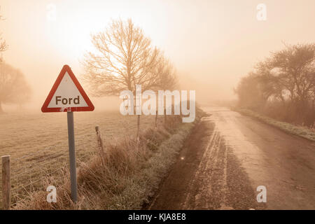 Un freddo gelido e gelido nebbiosa mattina presto a Ickham come il sole sorge, ghiaccio dalla Ford freezez sulla strada, vicino a Canterbury, Kent, Regno Unito Foto Stock