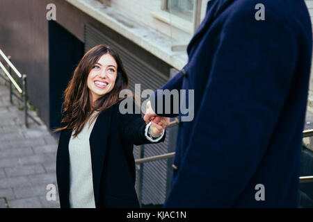 Bella e felice coppia in amore tenendo le mani mentre andando giù per le scale all'aperto Foto Stock