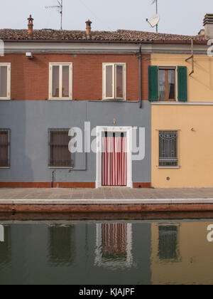 Comacchio, Fe, Italia - 4 novembre 2017: esterno rivolto verso la camera che si affaccia sul canal di Comacchio. riflesso nell'acqua. bianco porta di ingresso telaio w Foto Stock