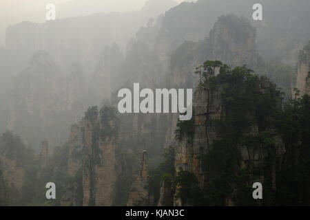 Fumoso il tramonto del zhangjiajie National Forest park's cime frastagliate e colonne di pietra calcarea nella provincia del Hunan in Cina Foto Stock