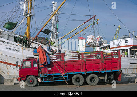 Il caricamento dei camion della merce da legno / pinisi phinisi, Indonesiano tradizionale nave da carico nel porto di Semarang, Giava centrale, Indonesia Foto Stock