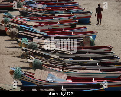 Un uomo a camminare sulla spiaggia di tarrafal nel Capo verde, tra piccole colorate barche di legno allineate sulla sabbia Foto Stock