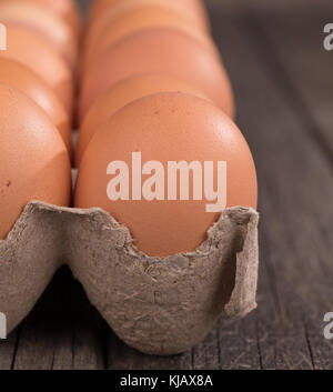 Primo piano della uova marrone in una scatola di cartone su una superficie di legno Foto Stock