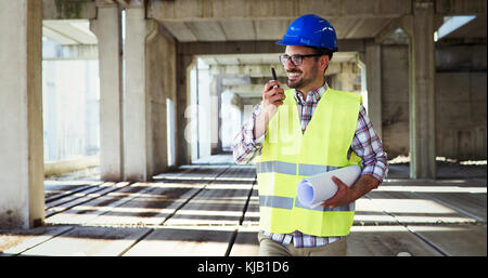 Architetto maschio con blueprint utilizzando un walkie-talkie Foto Stock