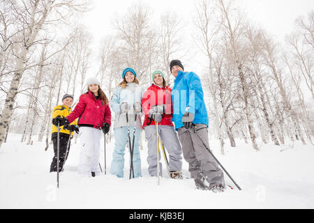 Ritratto di sorridente famiglia caucasica escursioni con le racchette da neve Foto Stock