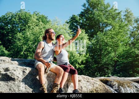 Coppia caucasica posa per telefono cellulare selfie sulle rocce Foto Stock