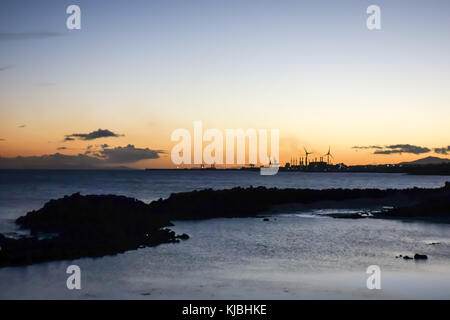 LANZAROTE, SPAGNA-4 novembre 2017: Tramonto nella principale località turistica della Costa Teguise con la centrale elettrica dell'isola per l'approvvigionamento energetico sul retro Foto Stock