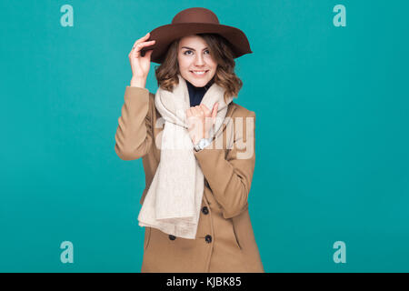 La felicità bella ragazza vestita in autunno ricoprire, cappello e sciarpa. studio shot, isolato su sfondo blu Foto Stock