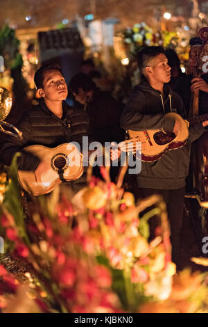 I musicisti suonano musica al gravesite di un membro della famiglia durante il festival Day of the Dead 1 novembre 2017 a Tzintzuntzan, Michoacan, Messico. La festa è stata celebrata fin da quando l'impero azteco celebra gli antenati e i defunti cari. Foto Stock