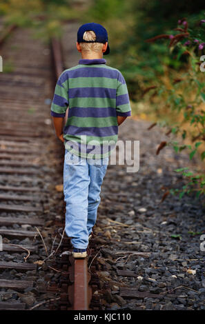Boy Walking lungo le piste del treno Foto Stock