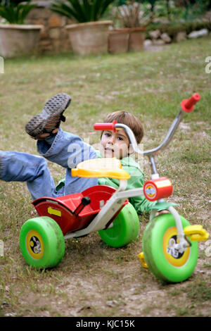 Ragazzo che cade dal triciclo Foto Stock