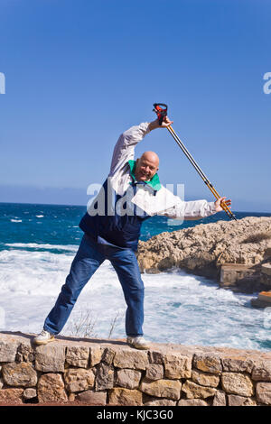 Nordic Walker in piedi dal mare tenendo i poli in aria Foto Stock