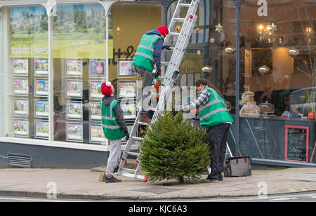 Persone vestite con cappelli di Natale mettendo su un albero di Natale in Arundel, West Sussex, in Inghilterra, Regno Unito. Foto Stock