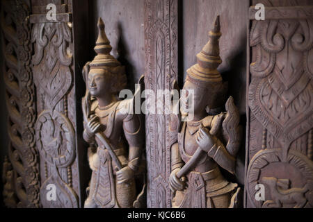 Ragnatela coperta scolpite figure in legno e pannelli entro la shwe in bin kyaung monastero, un bellissimo monastero in teak a Mandalay. Foto Stock