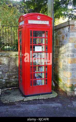 Tradizione, vecchia scatola del telefono rossa ora usata come luogo di scambio del libro, Netherbury, Dorset, Regno Unito - John Gollop Foto Stock