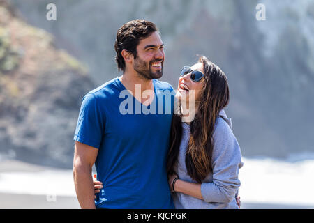Paio di ridere e abbracciando sulla spiaggia Foto Stock