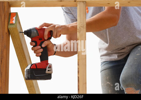 La donna caucasica legname di perforazione al sito in costruzione Foto Stock