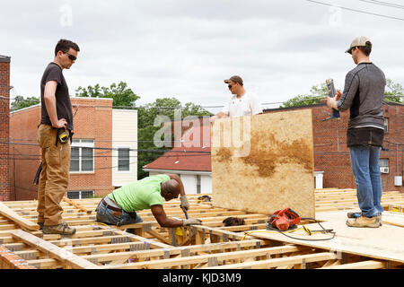 I volontari che operano sul tetto al sito in costruzione Foto Stock