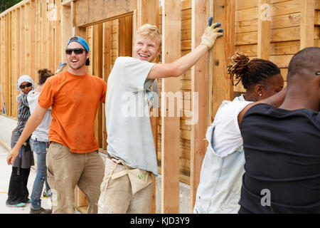 Volontari sorridente holding incorniciato muro al sito in costruzione Foto Stock